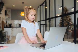 weinig meisje gebruik makend van tablet computer zittend Bij tafel foto