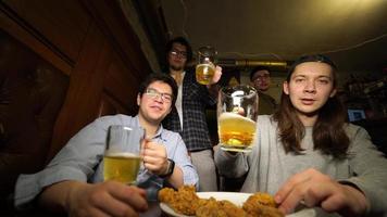 jong vrienden hebben pret samen drinken bier en gerinkel bril in een kroeg. foto