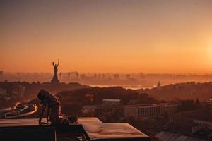 vrouw aan het doen yoga Aan de dak van een wolkenkrabber in groot stad. foto