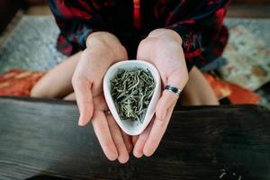 jong vrouw Holding een klein kom van groen kruiden thee foto