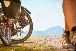 dichtbij omhoog bijhouden laag hoek terug visie van mannetje fietser wandelen naar weg toeren fiets geïsoleerd in toneel- weg panorama achtergrond. fiets toeren en krijgen fit concept foto