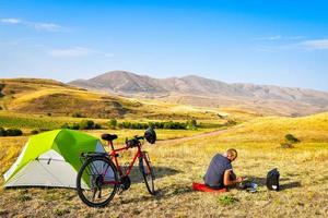 Kaukasisch persoon maken ontbijt vroeg ochtend- door tent solo. gezond levensstijl en fiets toeren. ecologisch reizen foto