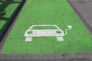 teken van een bezig met laden station voor elektrisch auto's geschilderd Aan een groen parkeren veel foto