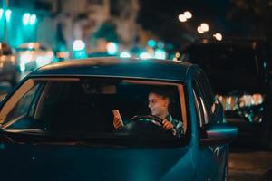 verloren vrouw bestuurder gebruik makend van mobiel telefoon terwijl het rijden Bij nacht. foto