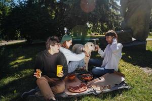 bedrijf van mooi jong mensen en hond hebben een buitenshuis lunch. foto