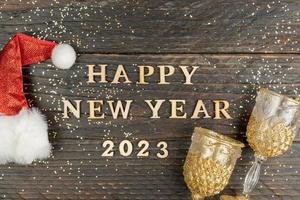 gelukkig nieuw jaar 2003 citaat gemaakt van houten brieven versierd met rood de kerstman hoed en twee Champagne bril. feestelijk groet kaart foto