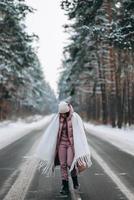 portret van een mooi Kaukasisch vrouw Aan een weg door besneeuwd Woud foto