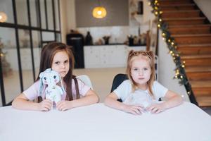 twee weinig zussen spelen samen Bij de tafel foto