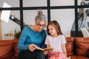mooi hoor ouderen vrouw grootmoeder lezing verhaal naar kleindochter. foto