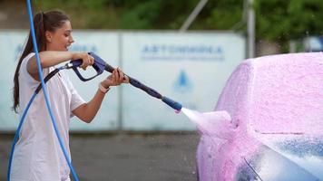 brunette van een hoge druk slang is van toepassing een schoonmaakster Aan de auto foto