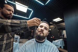 kapper werken met een baard klipper. hipster cliënt krijgen kapsel. foto