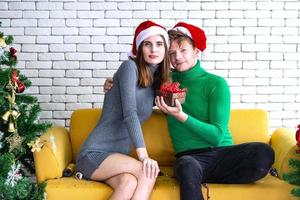 vrolijk Kerstmis en nieuw jaar concept. jong Kaukasisch minnaar met Kerstmis thema kleding vieren en uitwisseling presenteert elk andere in de partij met pret en geluk foto