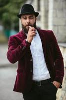 rijke man met een baard rookt elektronische sigaret foto