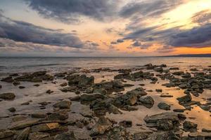 steen strand Bij zonsondergang. schemering zee en lucht. dramatisch lucht en wolken. natuur landschap. foto