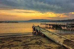 verbazingwekkend idyllisch zonsondergang of zonsopkomst Bij een kust met houten pieren foto