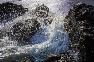 dichtbij visie van zee golven verpletterd Aan de rotsen. schoonheid water verstuiven foto