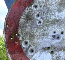 gedetailleerde close-up van kogelgaten van geweerschoten in een verkeersbord foto