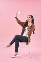 glimlachen jong vrouw maken selfie foto Aan smartphone over- roze achtergrond