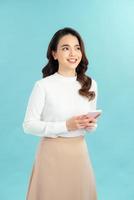 portret van een gelukkig Aziatisch zakenvrouw gebruik makend van mobiel telefoon geïsoleerd over- blauw achtergrond foto