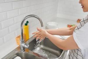 vrouw het wassen handen in keuken wastafel foto