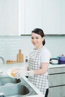 Aziatisch dame wassen een schotel in keuken kamer foto