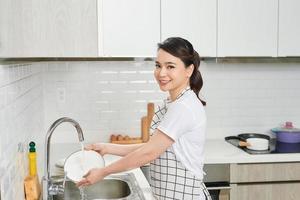 Aziatisch dame wassen een schotel in keuken kamer foto