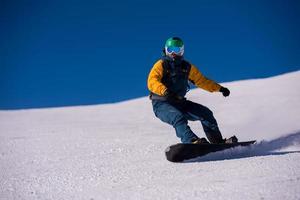 snowboarder rennen naar beneden de helling en rijden vrij stijl foto