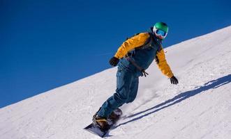 snowboarder rennen naar beneden de helling en rijden vrij stijl foto