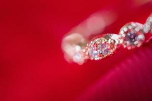 sieraden luxe roze goud ring met saffier edelsteen Aan rood kleding stof structuur achtergrond foto