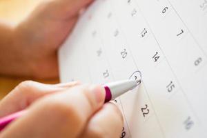 kalenderpagina met vrouwelijke hand met pen foto
