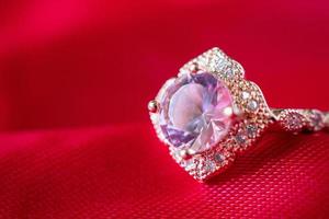 sieraden luxe roze goud ring met saffier edelsteen Aan rood kleding stof structuur achtergrond foto