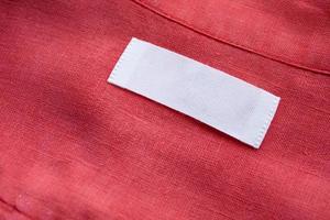 wit blanco kleding label etiket Aan rood linnen overhemd kleding stof structuur achtergrond foto