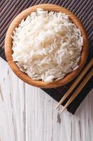 rijst in een houten kom en eetstokjes verticale bovenaanzicht foto