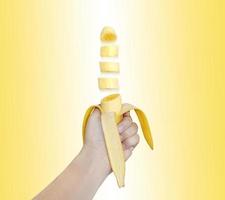 banaan geschild was draaide zich om naar stukken in zijn hand- Aan een wit geel achtergrond. de concept is eenvoudiger dan een kaal banaan. foto