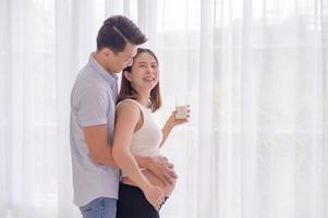 Aziatisch man knuffelen zijn vrouw wie is over naar drinken vers melk met liefde foto