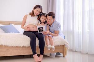 een Aziatisch familie, ouders en dochters zijn aan het kijken een echografie film van een kind in hun moeder baarmoeder foto