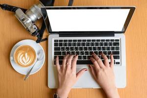 vrouw handen typen Aan een laptop toetsenbord met geïsoleerd scherm en koffie kom tot rust tijd foto