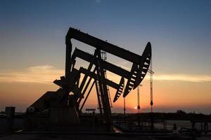 olie tuigage of olie veld- plaats, in de ochtend- of avond, olie pompen zijn rennen, de olie pomp en de mooi zonsondergang of zonsopkomst van pompen eenheid. foto