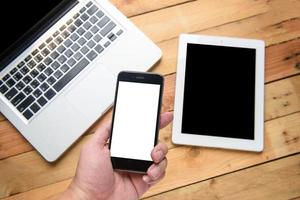 detailopname beeld van een hand- Holding smartphone met tablet computer en laptop achtergrond foto