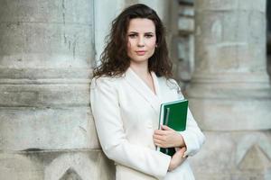 portret van een bedrijf vrouw met een notitieboekje in haar hand. slim gekleed meisje buiten. geslaagd wit Europese vrouw foto