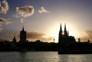 de zon sets in de midden- van de torens van Keulen kathedraal foto