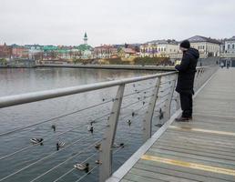 de Mens feeds de eenden in de meer. bewolkt, herfst dag in Rusland. verkoudheid het weer. stad landschap, straat foto