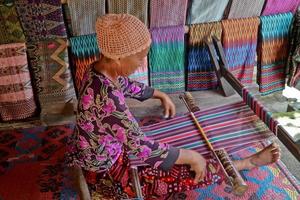 droevig dorp, lombok, Indonesië, juni 2021- een vrouw weeft garen naar worden gebruikt net zo sesek foto