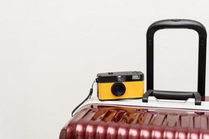 reizen concept wijnoogst camera Aan rood bagage grijs achtergrond, met kopiëren ruimte. koffer en retro film camera reizen concept. foto