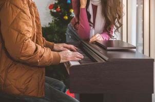 paar genieten van Super goed tijd in leven kamer met piano. Mens spelen piano en het zingen voor vrouw. vieren winter vakantie samen Bij huis. foto