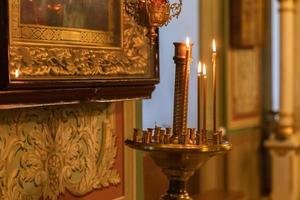 orthodoxe kerk. Christendom. feestelijke interieurdecoratie met brandende kaarsen en icoon in traditionele orthodoxe kerk op paasavond of kerstmis. religie geloof bidden symbool. foto