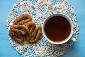 papaver met pretzels Aan een blauw bord met een kop van thee. een kop van thee en pretzels met kaneel. foto