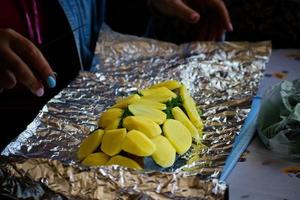 vrouw is Koken Zalm vis met met aardappelen en en dille in folie. foto