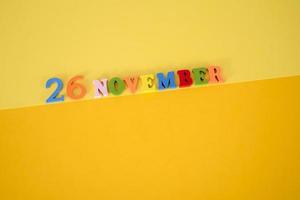 november 26 Aan een geel en papier achtergrond met houten en veelkleurig brieven met ruimte voor tekst. foto