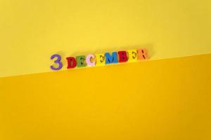 december 3 Aan een geel en papier achtergrond met houten en veelkleurig brieven met ruimte voor tekst. foto